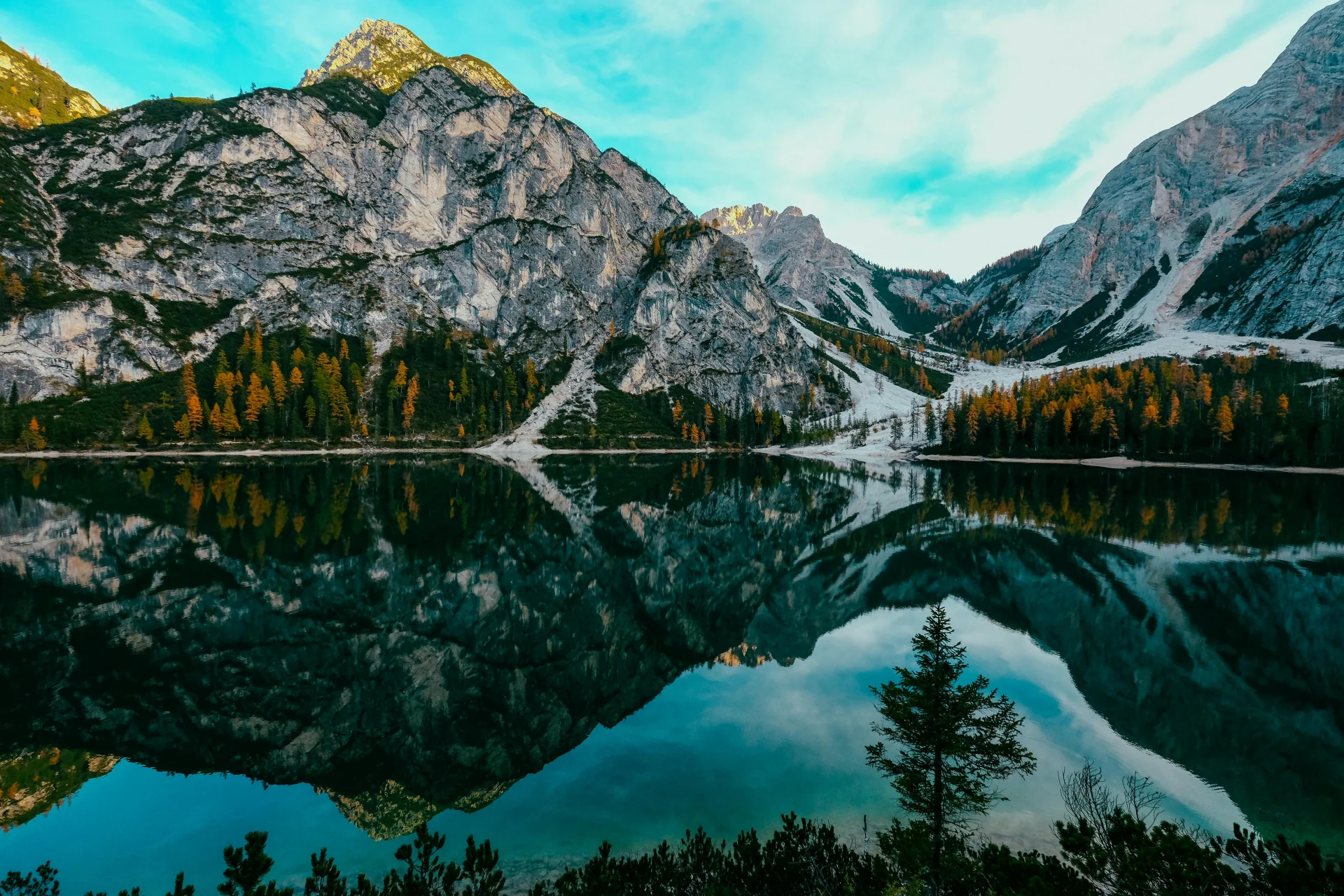 Cadeia de montanhas refletida em lago tranquilo ao amanhecer.